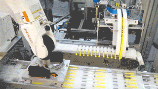 a robotic arm on a packing machine placing sterile prefilled syringes on a packing tray
