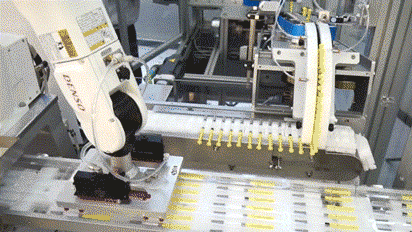 a robotic arm on a packing machine placing sterile prefilled syringes on a packing tray